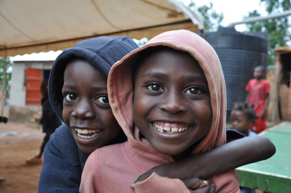Two children laughing together outside a community centre.